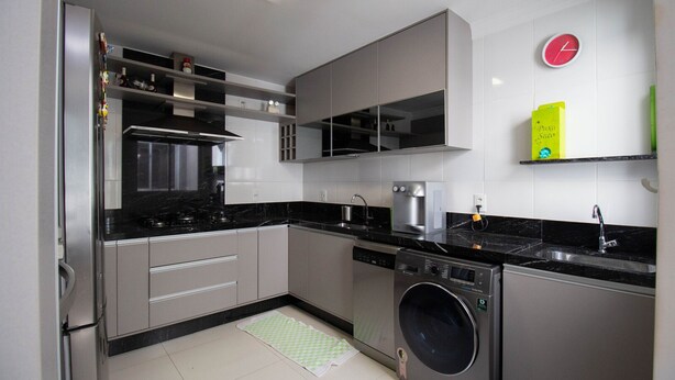 A modern kitchen with stainless steel appliances, a built-in oven, and a washing machine. - Apto c Conforto Tecnologia a 10 min do Aeroporto (Nucleo Bandeirante)