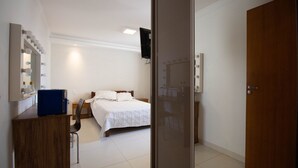 A hotel room with a bed, a desk with a mirror, and a television. - Apto c Conforto Tecnologia a 10 min do Aeroporto (Nucleo Bandeirante)