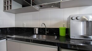 A kitchen with a stainless steel sink, a green container, and a water dispenser. - Apto c Conforto Tecnologia a 10 min do Aeroporto (Nucleo Bandeirante)