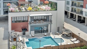 A modern building with a rooftop garden, a swimming pool, and outdoor seating areas. - Latitude Apartments (Metairie)