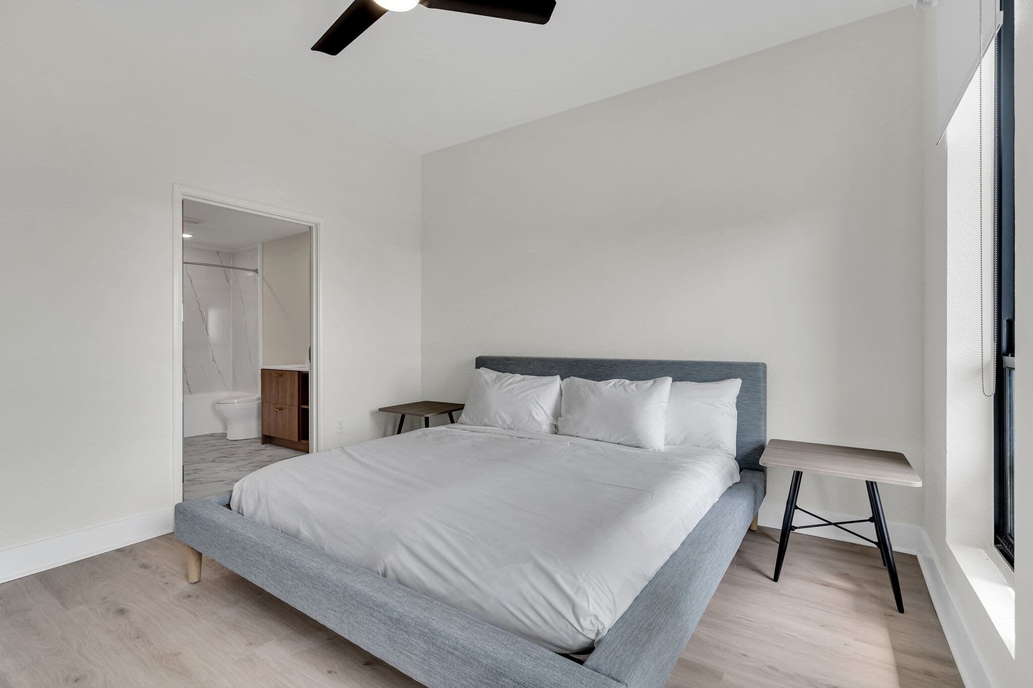 Quarto moderno com cama, mesas de cabeceira e uma janela.