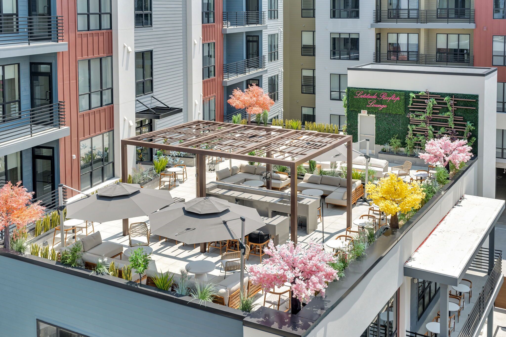 A rooftop lounge with outdoor seating, greenery, and a sign for Latitude Rooftop Lounge.