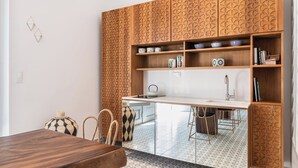 A modern kitchen with a wooden cabinet, a white countertop, and a patterned backsplash. - Upscale 2-bedroom villa in the Venetian Harbour (Chania)
