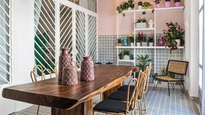 A dining area with a wooden table, wicker chairs, and a potted plant on a shelf. - Upscale 2-bedroom villa in the Venetian Harbour (Chania)