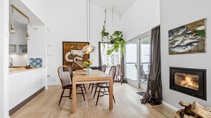 Een moderne eetruimte met een houten tafel en stoelen, een hangplant en een open haard.