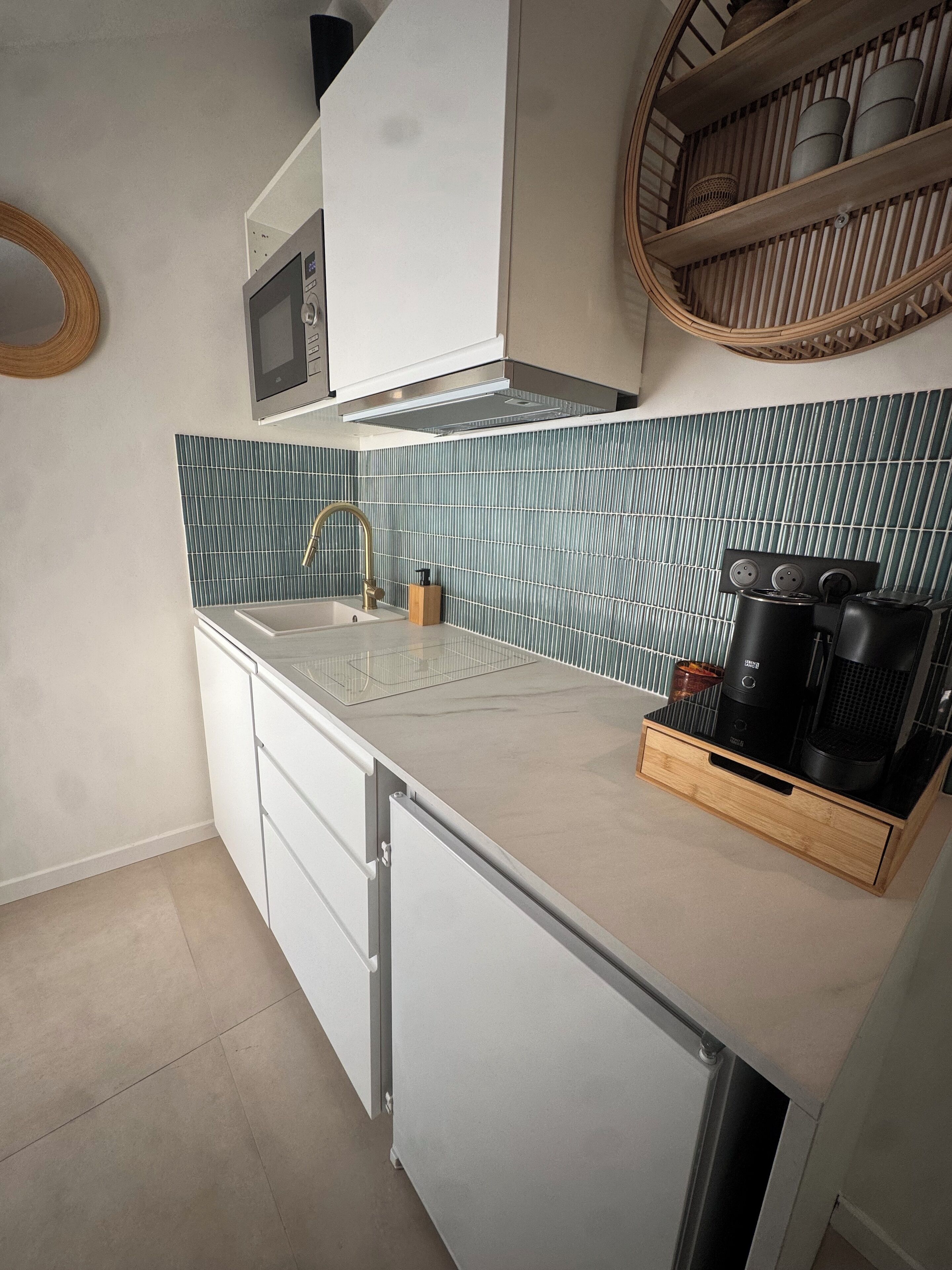 A modern kitchen with a white countertop, a stainless steel sink, and a built-in microwave.