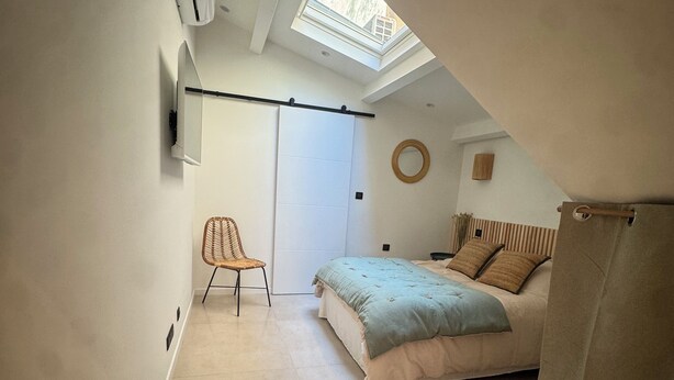 Une chambre à coucher comprenant un lit, une chaise, une lucarne et une porte coulissante.