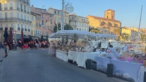 Une rue pavée où se trouve un étal de marché vendant divers articles.