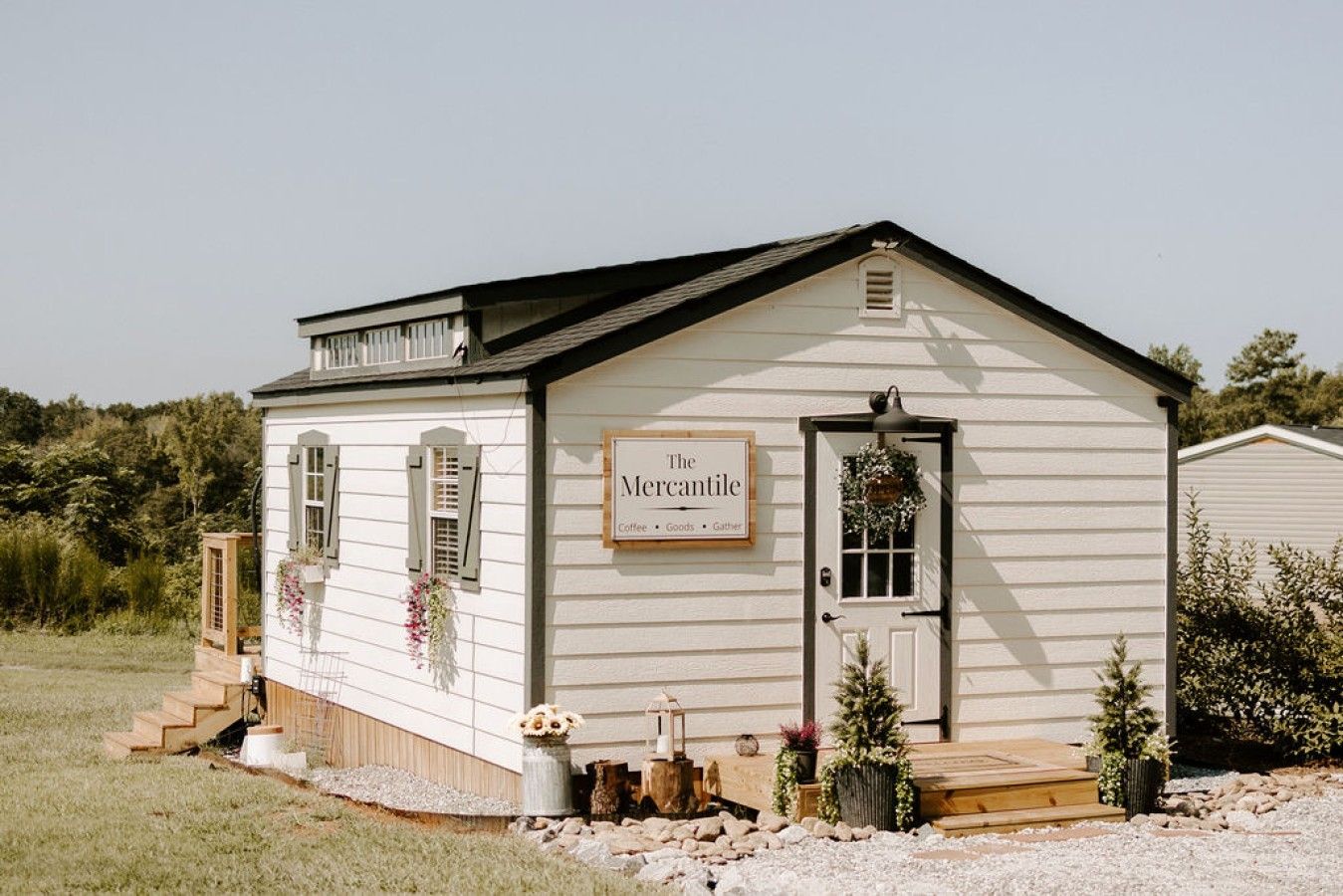 A small, single-story building with a sign reading 'The Mercantile,' featuring a front door, windows, and a small porch area.