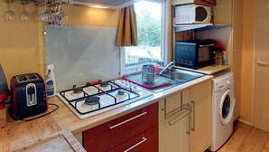 Cocina compacta equipada con estufa a gas, microondas y lavadora.