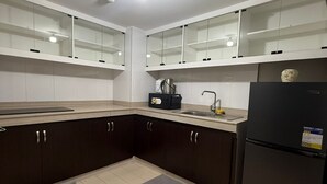 A modern kitchen with dark cabinets, a black refrigerator, and a tiled floor. - Califnia Gardens Square (Mandaluyong)