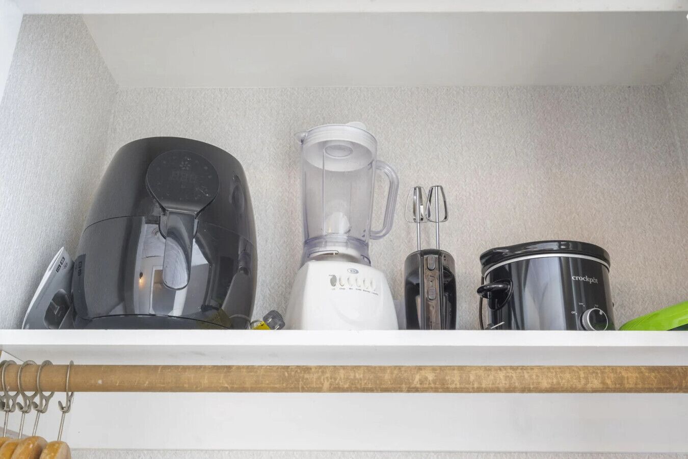 Uno scaffale in cucina con una macchina da caffè, un frullatore e una pentola a cottura lenta.