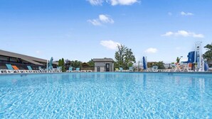 Una piscina con lettini e uno scivolo acquatico.