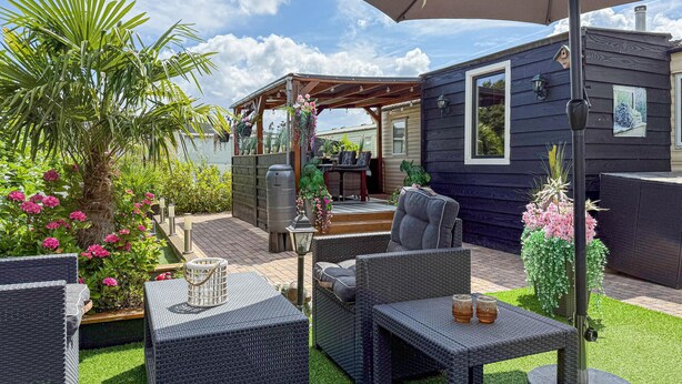 Un patio con mobiliario exterior, una parrilla y una pequeña construcción de madera.