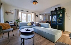 Una sala de estar moderna con un sofá azul claro, una mesa de centro redonda y un suelo de madera oscura.