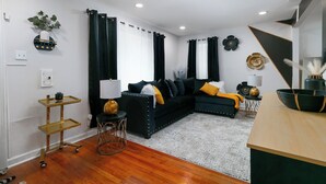 Una sala de estar moderna con un sofá oscuro, una mesa de centro de madera y una mesita auxiliar con una lámpara.