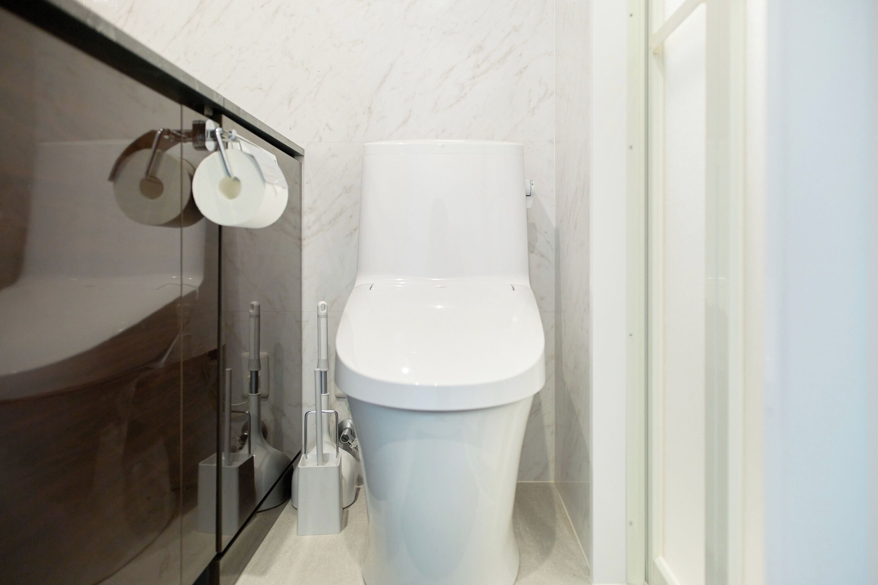 Ein modernes Badezimmer mit Toilette, Duschkabine aus Glas und Marmorwand.