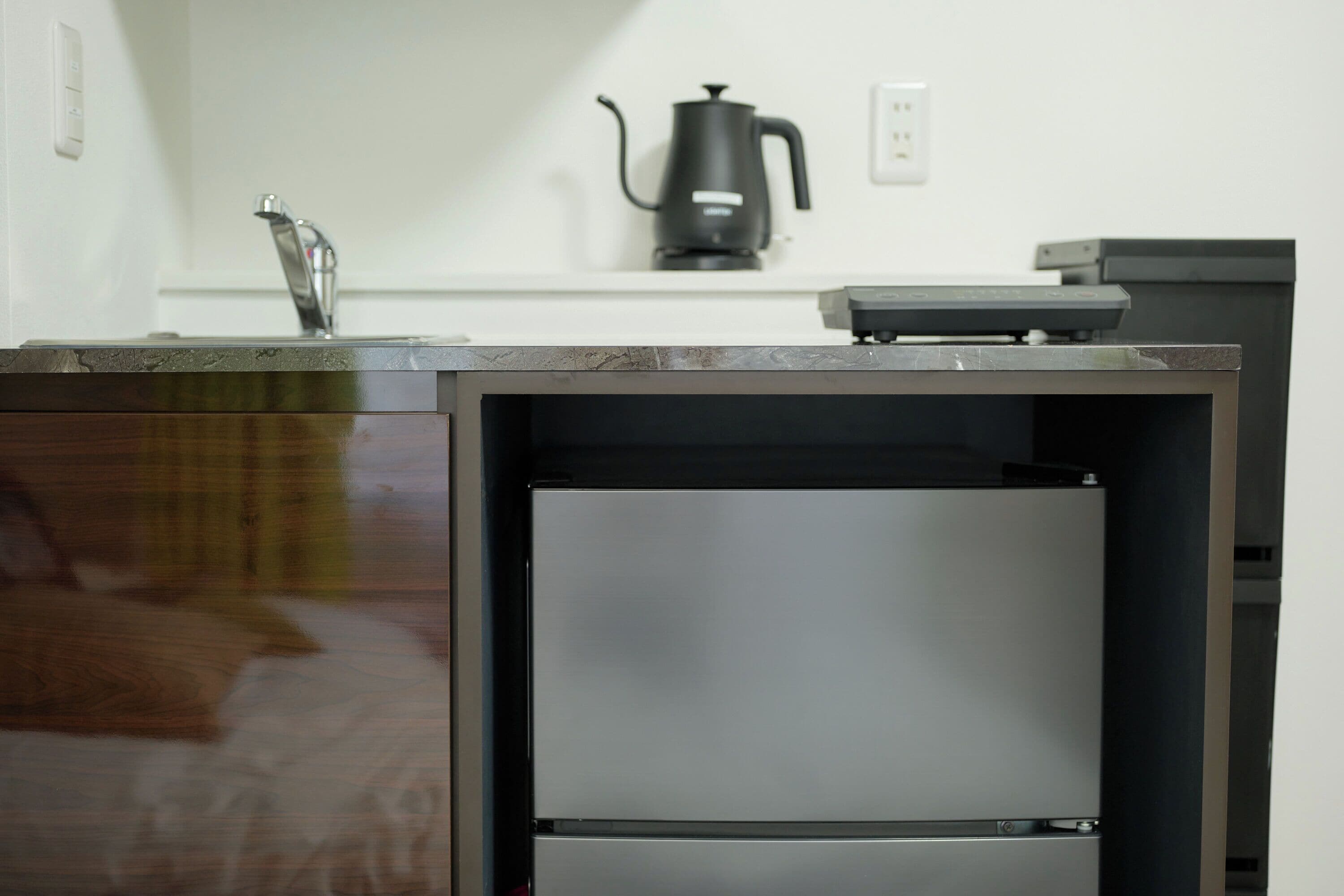 A kitchen with a built-in refrigerator, a coffee maker, and a sink.