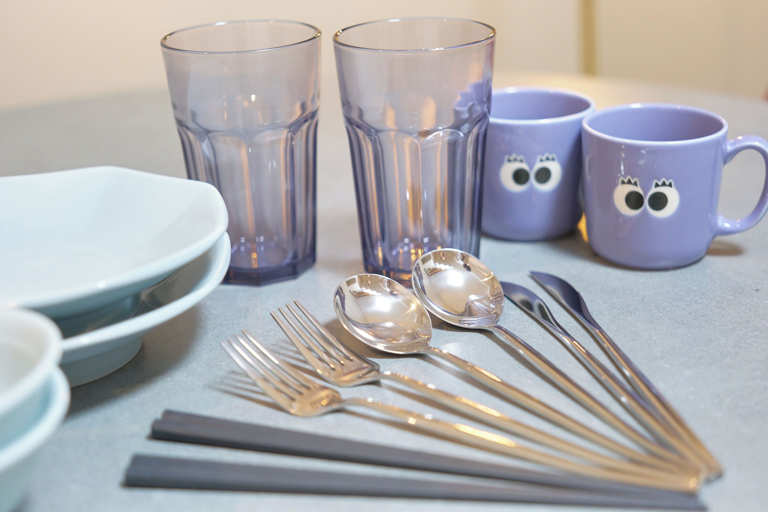 A table set with clear glassware, spoons, forks, and plates.