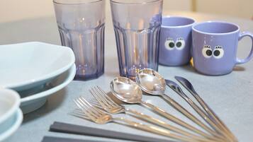 A table set with clear glassware, spoons, forks, and plates.