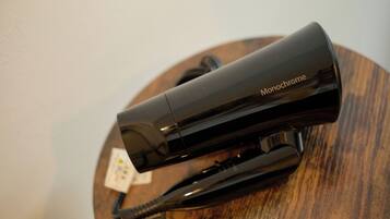 A black hairdryer with a cord and a plug on a wooden surface.