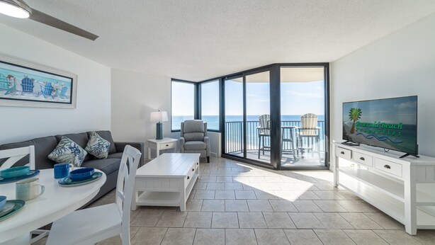 A modern living room with a balcony, white furniture, and a television.