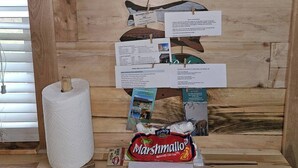 A wooden wall with a horse painting, a tissue roll, a bag of marshmallows, and informational cards.