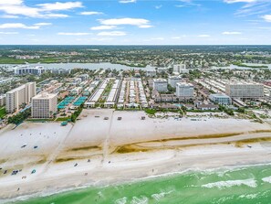 An aerial view of a coastal resort with beachfront properties, a marina, and a beach.