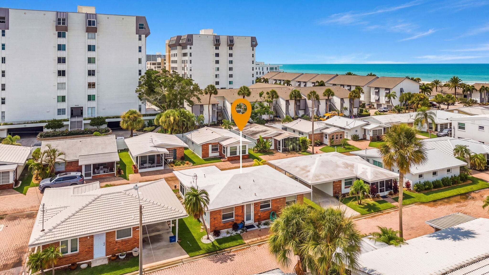 Uma área residencial costeira com várias casas térreas, um grande hotel e vista clara para o oceano.