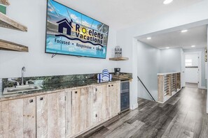 A modern kitchen with a wooden cabinet, a stainless steel sink, and a large sign advertising 'Ravens' vacation rentals.