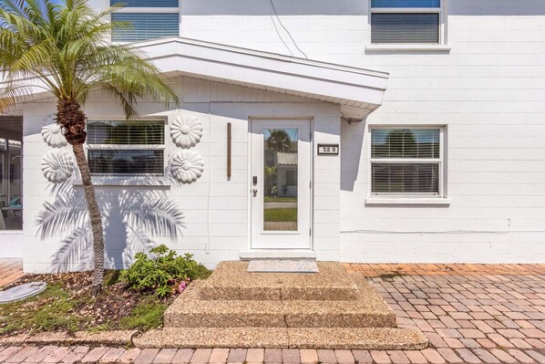 A white building with a door marked '52S' and a palm tree in front.
