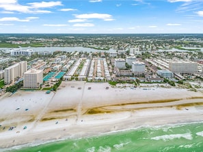 An aerial view of a coastal resort with beachfront properties, a marina, and a beach.