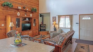 A cozy living room with wooden walls, a television, a fireplace, and a comfortable seating area. - Big Pines Ponderosa Cabin (Overgaard)