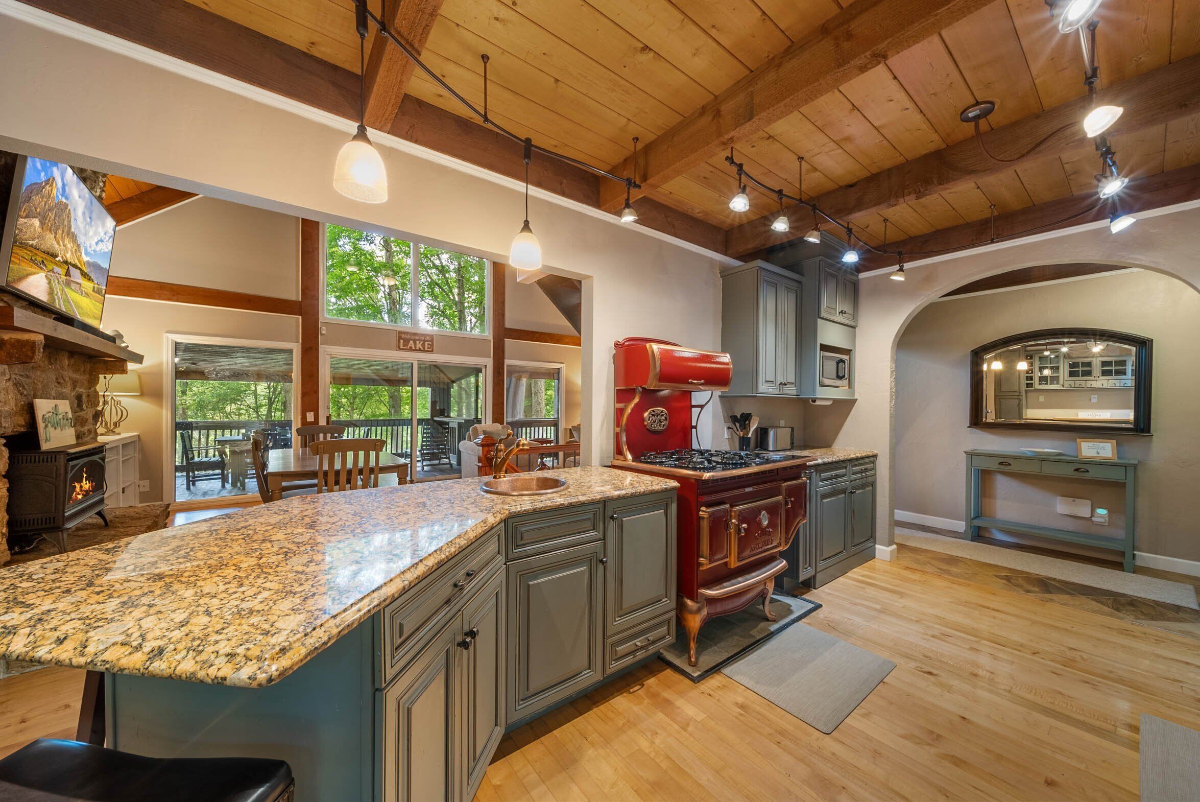 A spacious kitchen with granite countertops, a red stove, and a view of a lake.