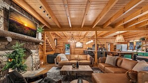 L’intérieur chaleureux d’un chalet en bois comprend une cheminée en pierre, des canapés en cuir, des poutres en bois et un coin cuisine.