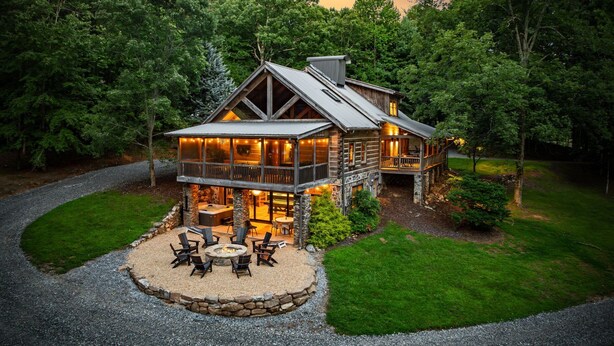 Une cabane en rondins dotée d’une terrasse, d’un espace salon extérieur et d’un foyer.