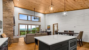 Una cocina amplia con una isla grande, piso de madera y una pared de acento de piedra.