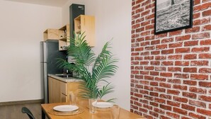 A dining area with a wooden table, black chairs, and a brick wall with a framed picture. - Apartment next to the Malecon of La Paz BCS "DON MANOLO". (La Paz)