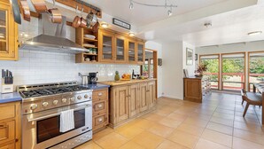A spacious kitchen with wooden cabinets, a stainless steel stove, and a large window overlooking a garden. - New Listing! Water & Vine In Sebastopol (Sebastopol)
