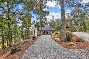 Une maison avec une allée en gravier, entourée d’arbres.