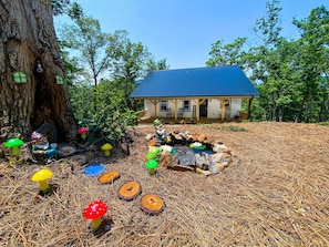 A rustic cabin with a blue roof, surrounded by a forest.
