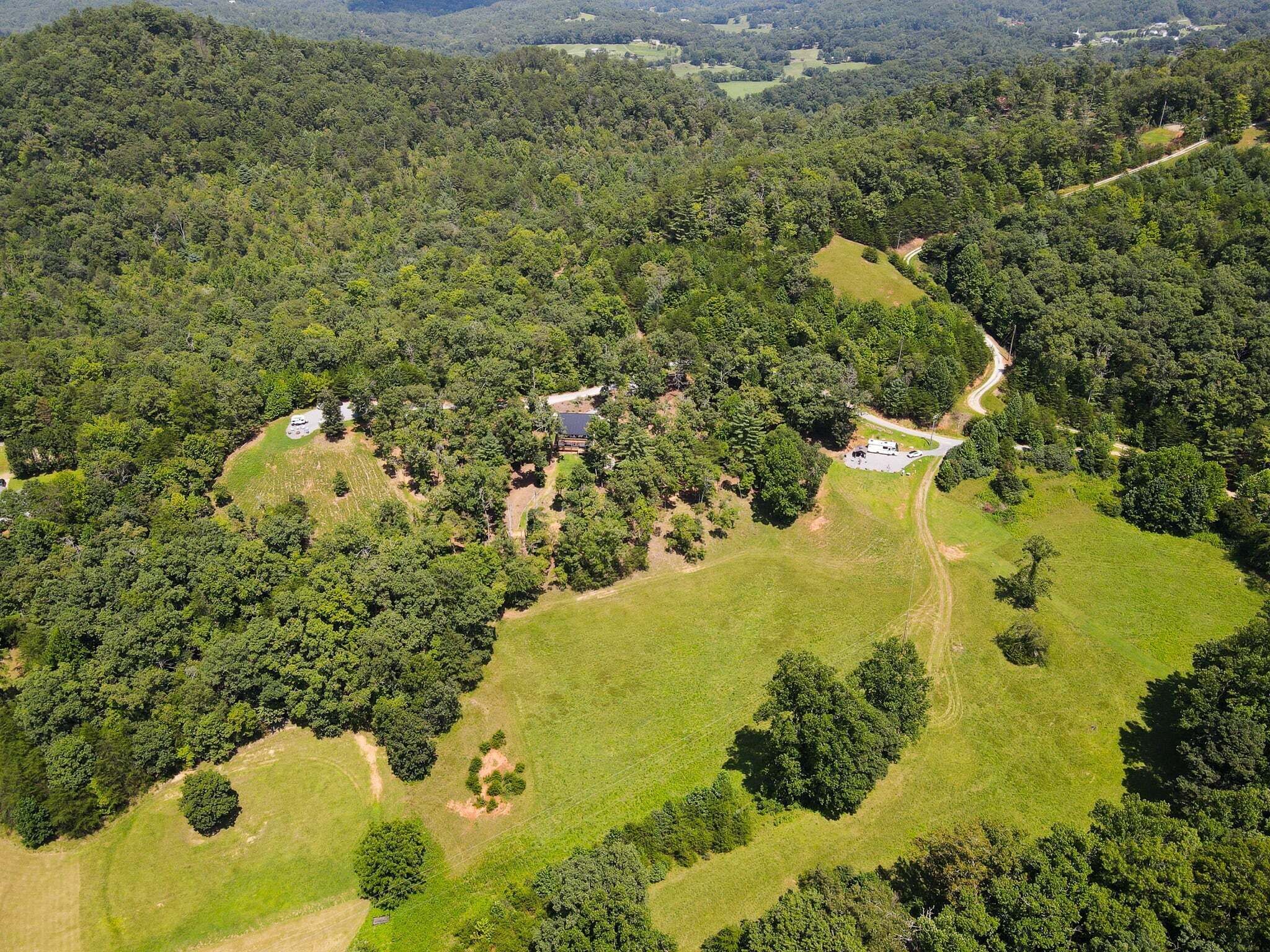 A large, open grassy area with scattered trees and a few buildings.