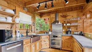 A wooden cabin kitchen with a stainless steel sink, oven, and a no smoking sign. - The Cabin - 2 Bedroom with Breathtaking Mountain Views! Hot Tub, and Game Room (Sevierville)