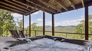 A hot tub with a wooden deck and chairs, overlooking a mountainous landscape. - The Cabin - 2 Bedroom with Breathtaking Mountain Views! Hot Tub, and Game Room (Sevierville)