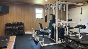 Une salle de sport équipée de matériel de musculation, d’haltères et de bancs.