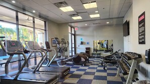 Une salle de sport équipée de tapis de course, de vélos elliptiques et de bancs de musculation.