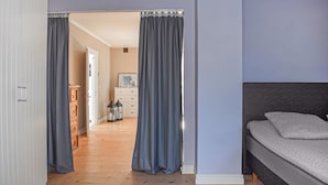 Een slaapkamer met een bed, een dressoir en een gang naar een andere kamer.