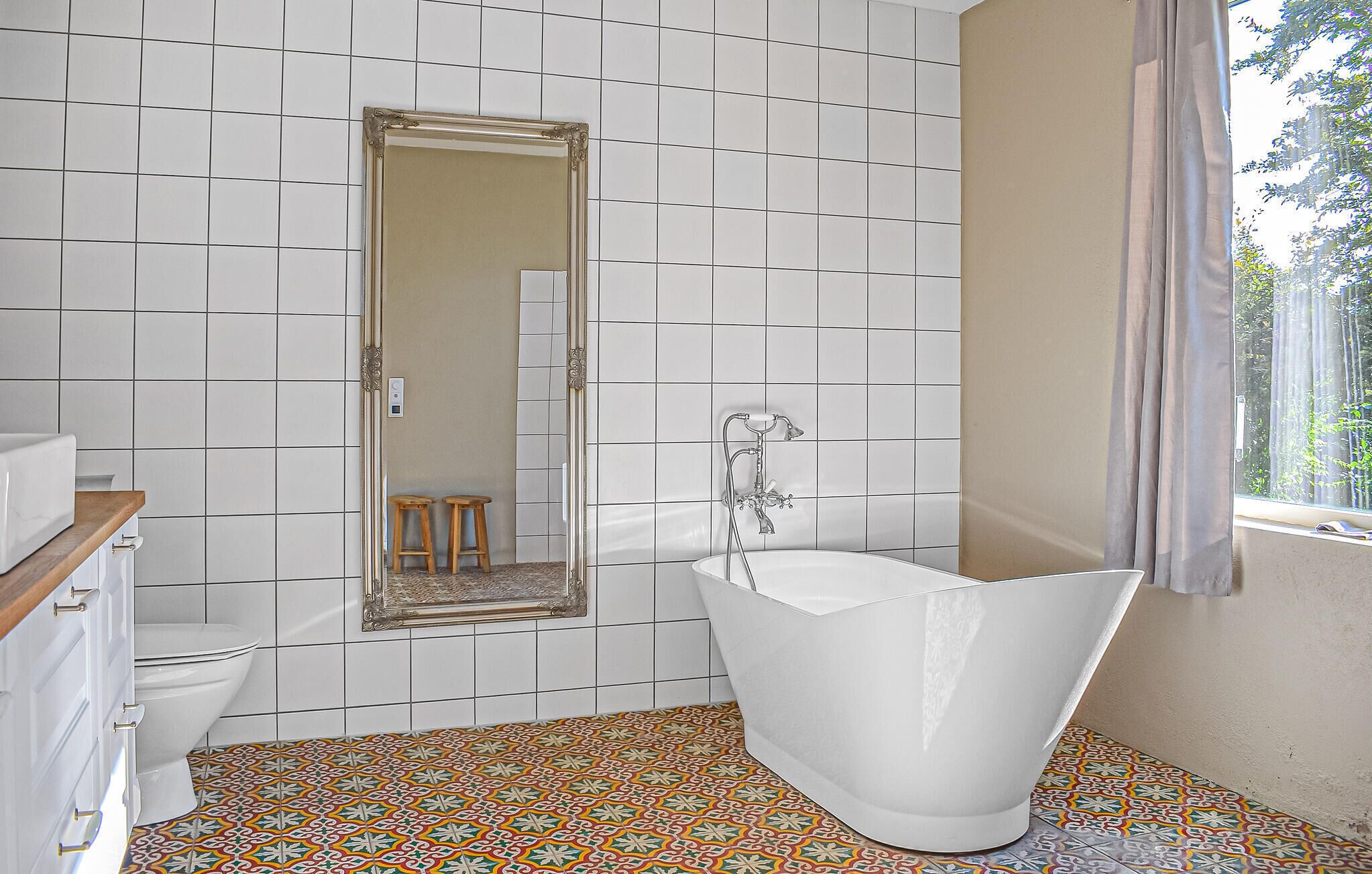 A bathroom with a freestanding bathtub, a toilet, a sink with a wooden countertop, and a mirror.