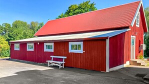 A red barn with a sloped roof, a bench outside, and a small porch area. - Amazing home in Holmsjö (Holmsjö)