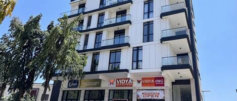 A multi-story building with commercial spaces on the ground floor, including a store named VIDYA.
